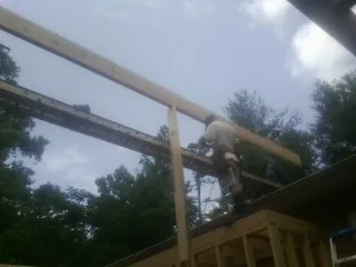 Carpenter setting a ridge beam over a new addition frame — Ice Dam Removal by Roofing Brothers in Earlham