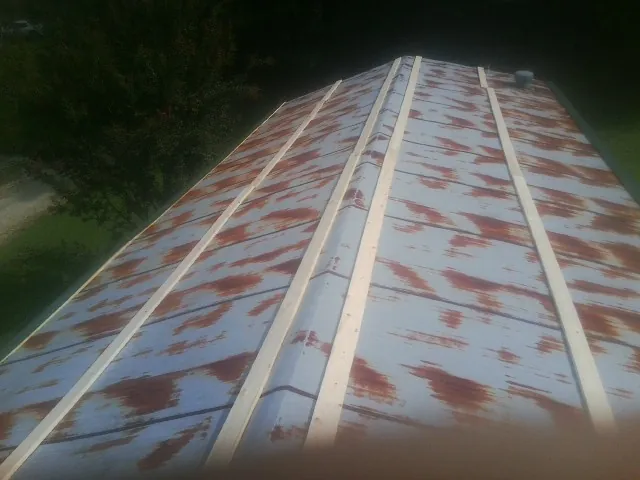 Rusted metal roof panels with new wood purlins before replacement — Storm Damage Roof Repair in Earlham by Roofing Brothers
