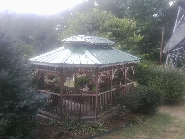 Green metal roof on a backyard gazebo surrounded by garden beds in Earlham
