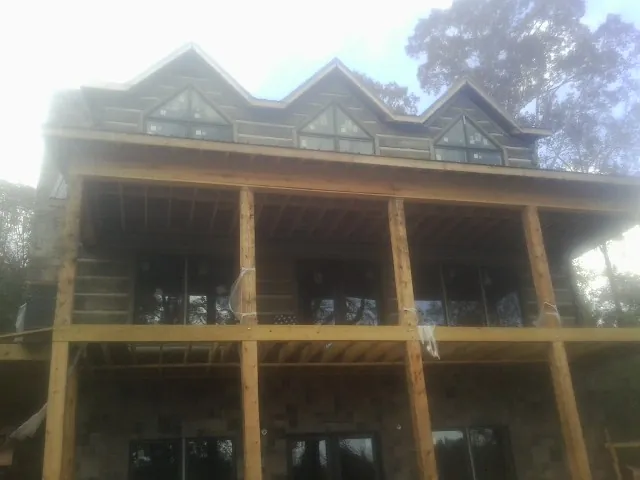 Dormers and porch framing on a large log home under construction — Roof Coating work by our crew in Earlham