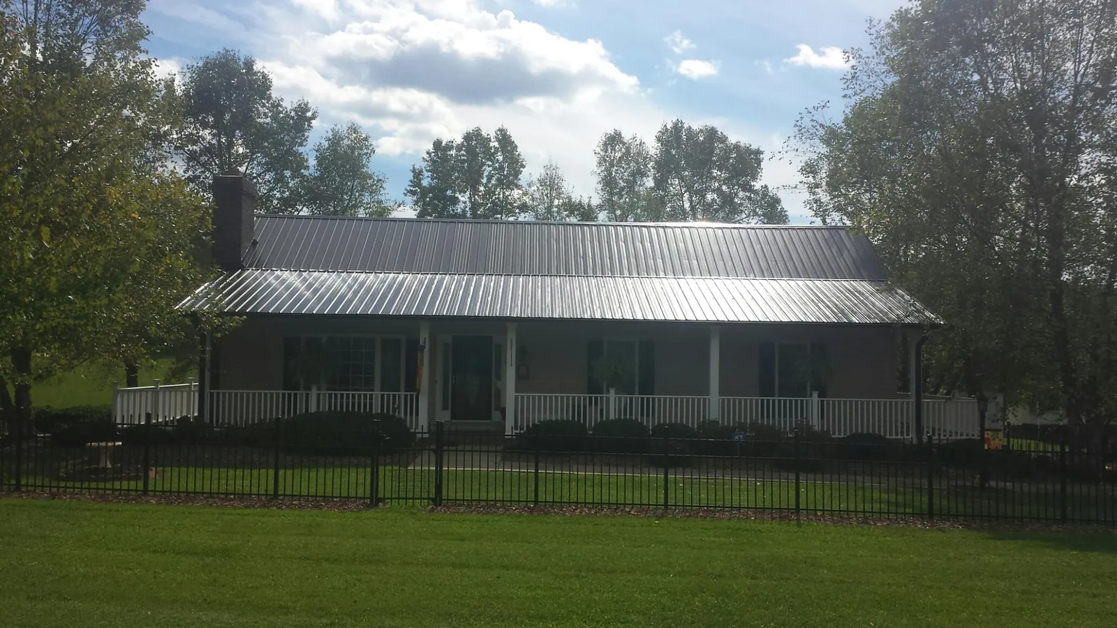 Gray metal roof on a brick ranch with a full width front porch — Gutter Guard Installation work by our crew in Earlham