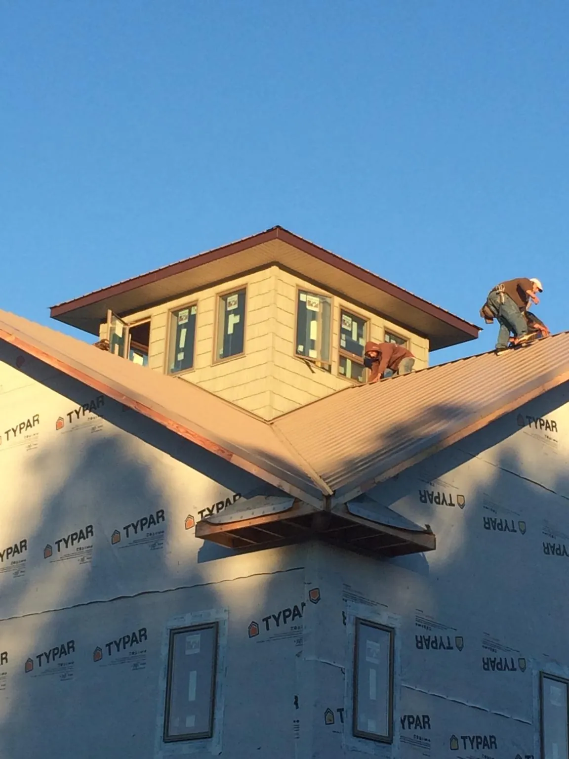 Roofers working around a rooftop cupola on a new metal roof at sunset — Roof Waterproofing in Earlham by Roofing Brothers